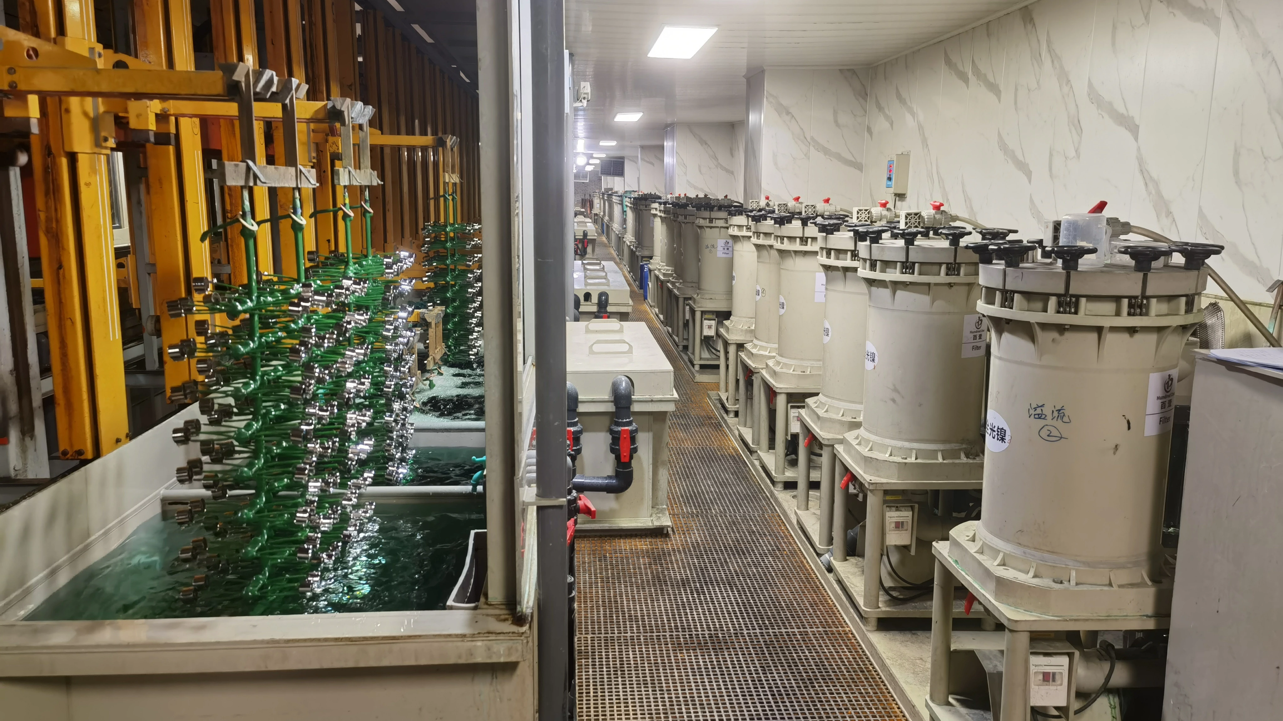 Rack electroplating line with loaded workpiece racks and adjacent filtration units